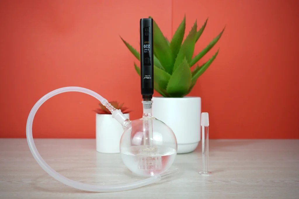 XMAX V4 Pro vaporizer connected to a glass globe bubbler water pipe with whip attachment